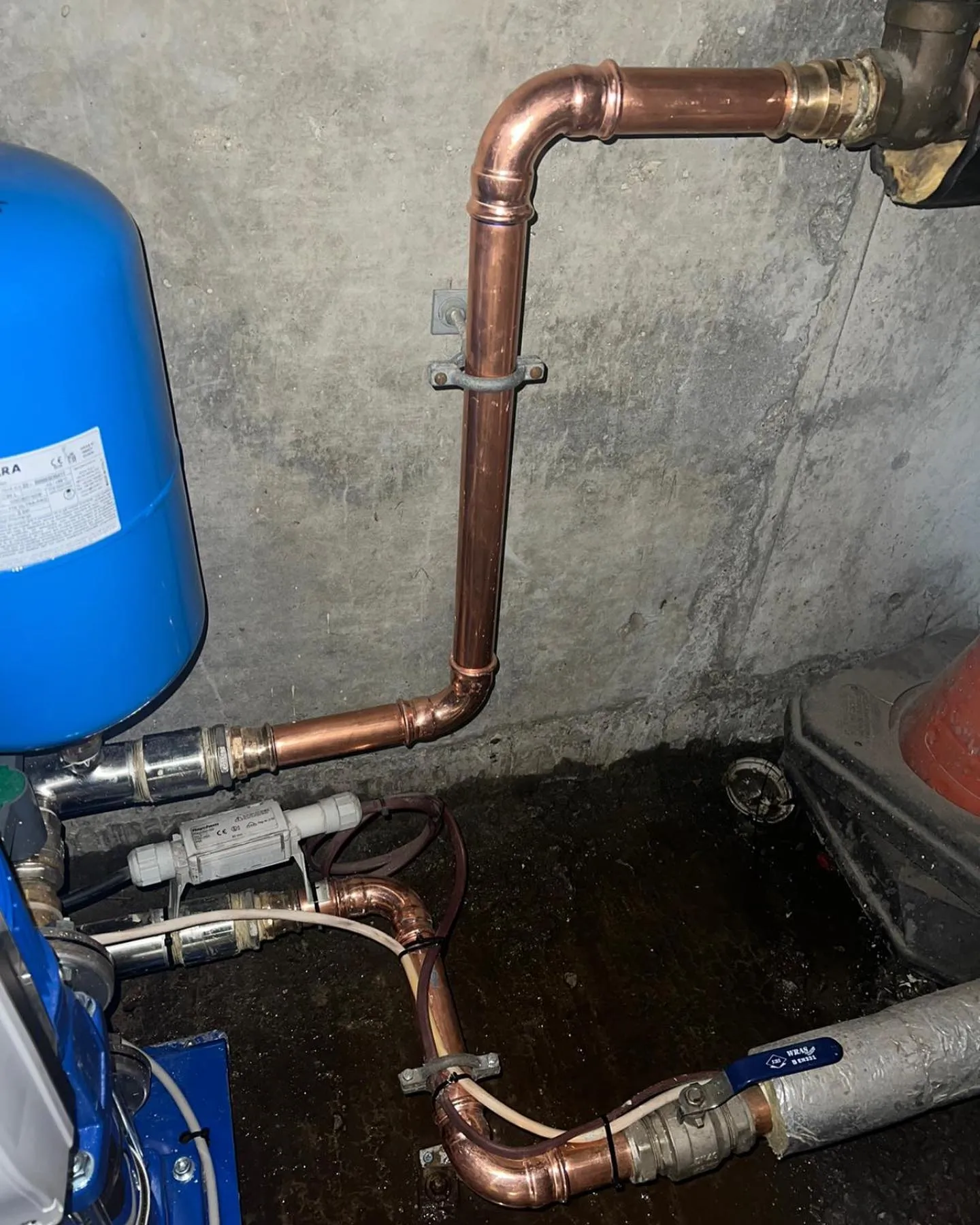 A water heater and pipes in a room.