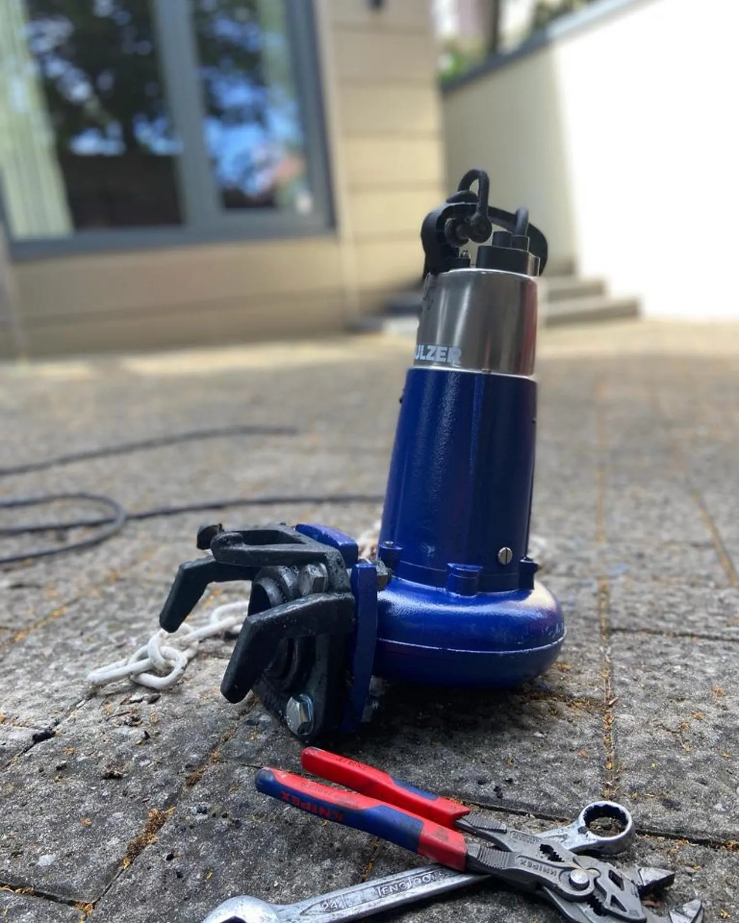 A pair of pliers and a wrench on the ground.