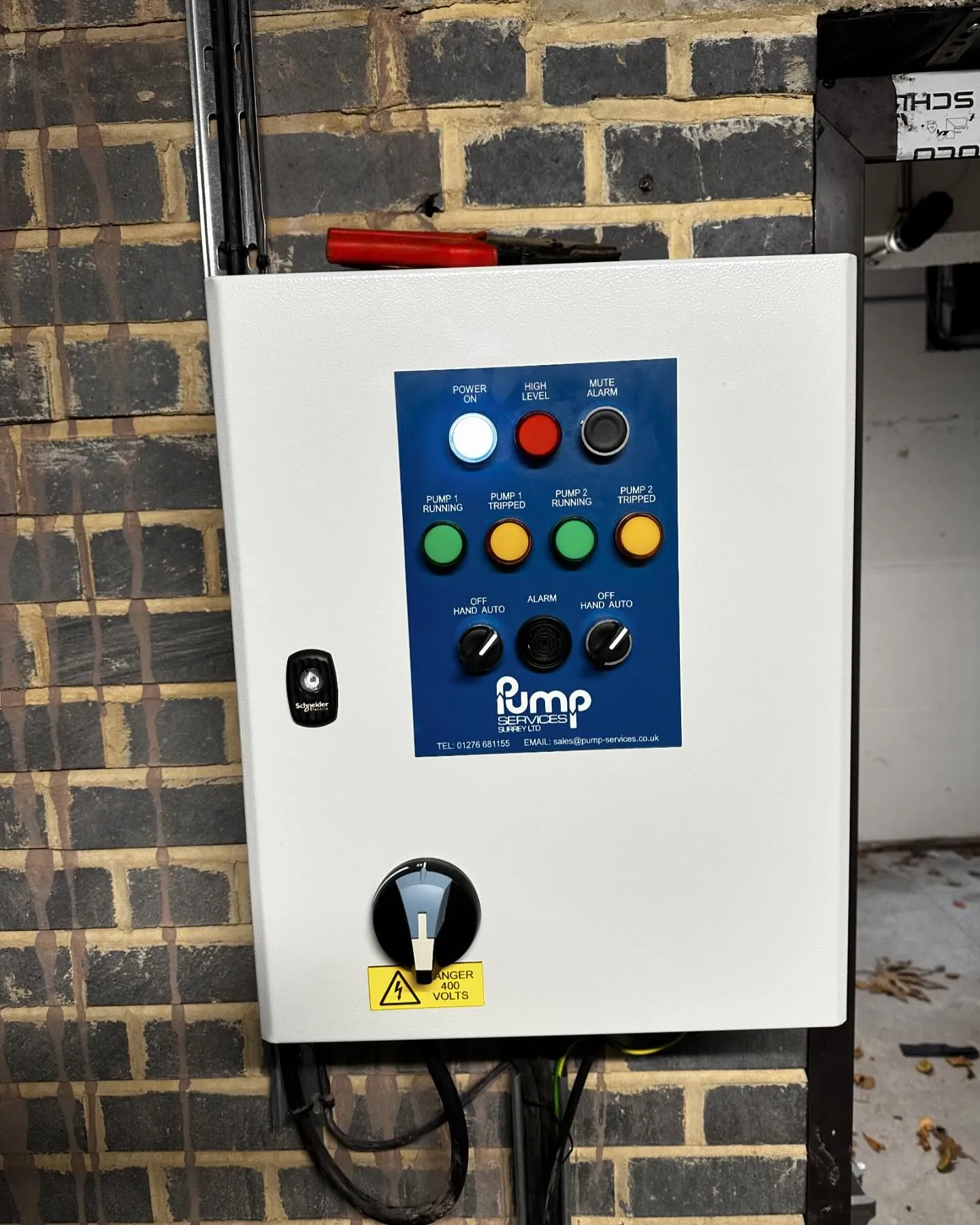 A control panel on a brick wall in a building.