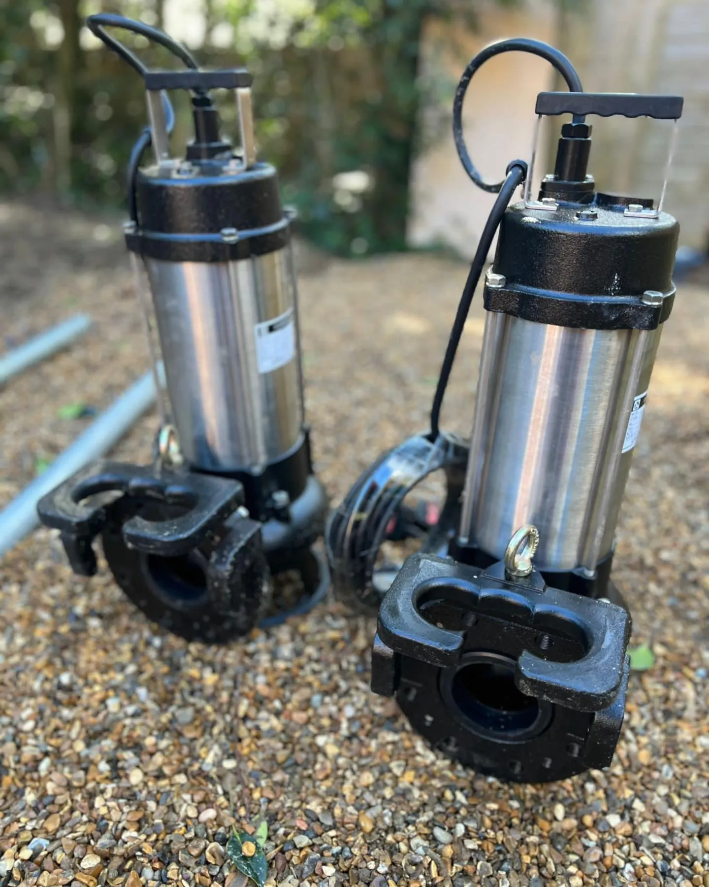 A couple of water pumps sitting on top of a gravel ground.
